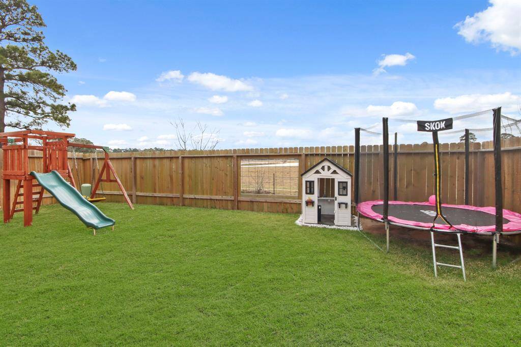 Spacious backyard with a well-maintained lawn enclosed by a wooden fence. You'll notice the custom "cut out window" in the back fence, perfect for watching the friendly cows grazing in the pasture. Ideal space for family fun and outdoor activities.