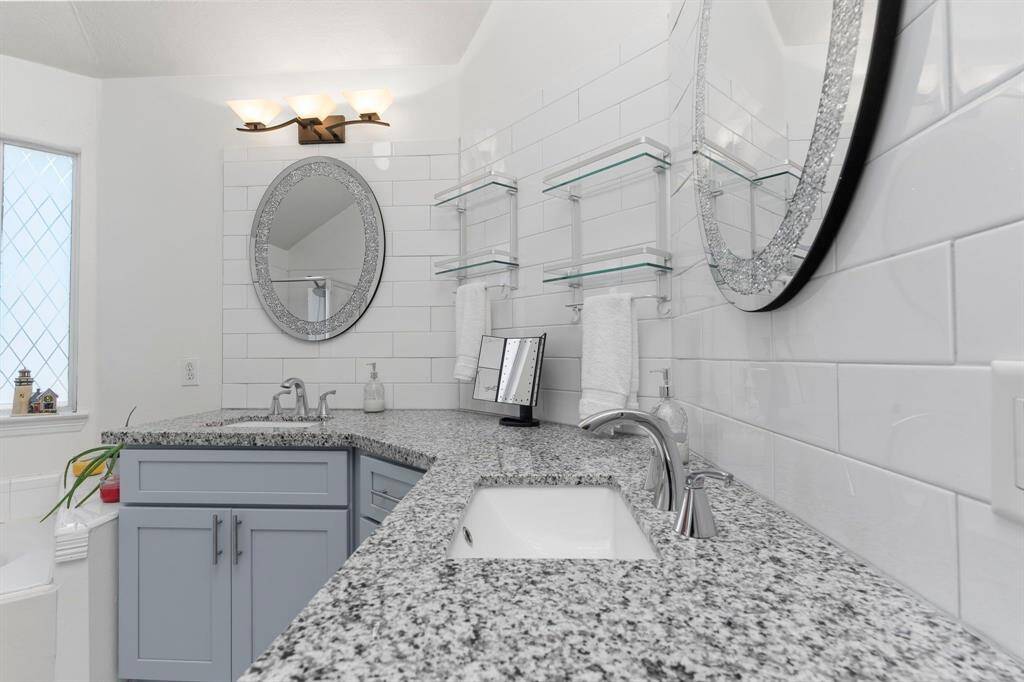 This spa-like primary suite bathroom is designed for two, featuring deep undermount sinks, a stunning subway tile backsplash, and so much more!
