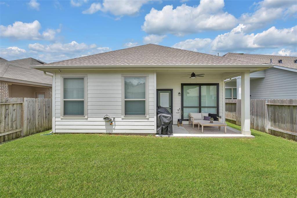 The expansive backyard offers a covered patio with a ceiling fan, plenty of space for a grill and patio furniture.