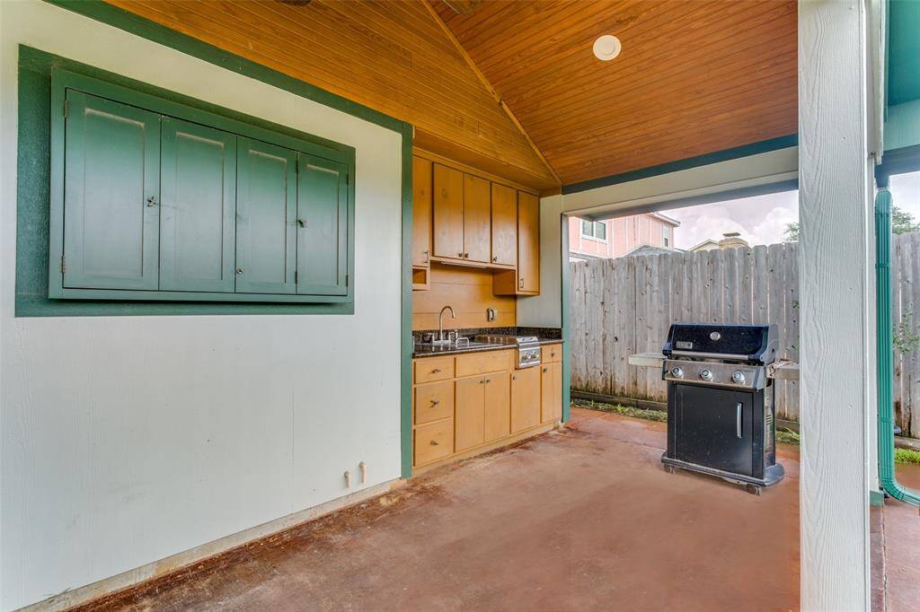 The outdoor kitchen area has space for a 65” TV with protective doors, stainless sink with cover, 2 burner propane cooktop, ceiling fan and lighting with plenty of custom built cabinets and drawers for storage.