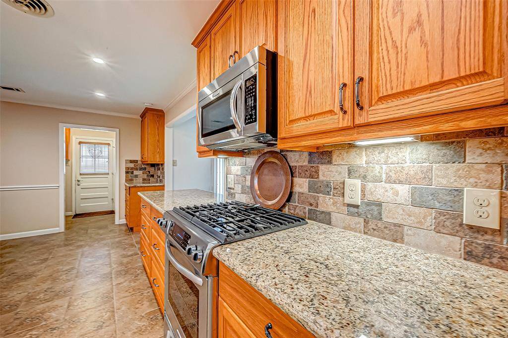 This kitchen features expansive granite countertops, providing ample space for meal preparation and entertaining. The sleek gas range offers precision cooking, perfect for culinary enthusiasts. Custom cabinetry enhances both style and functionality, with soft-close drawers and doors ensuring a smooth, quiet operation. Additionally, pull-out drawers maximize storage efficiency, making it easy to access cookware and essentials.