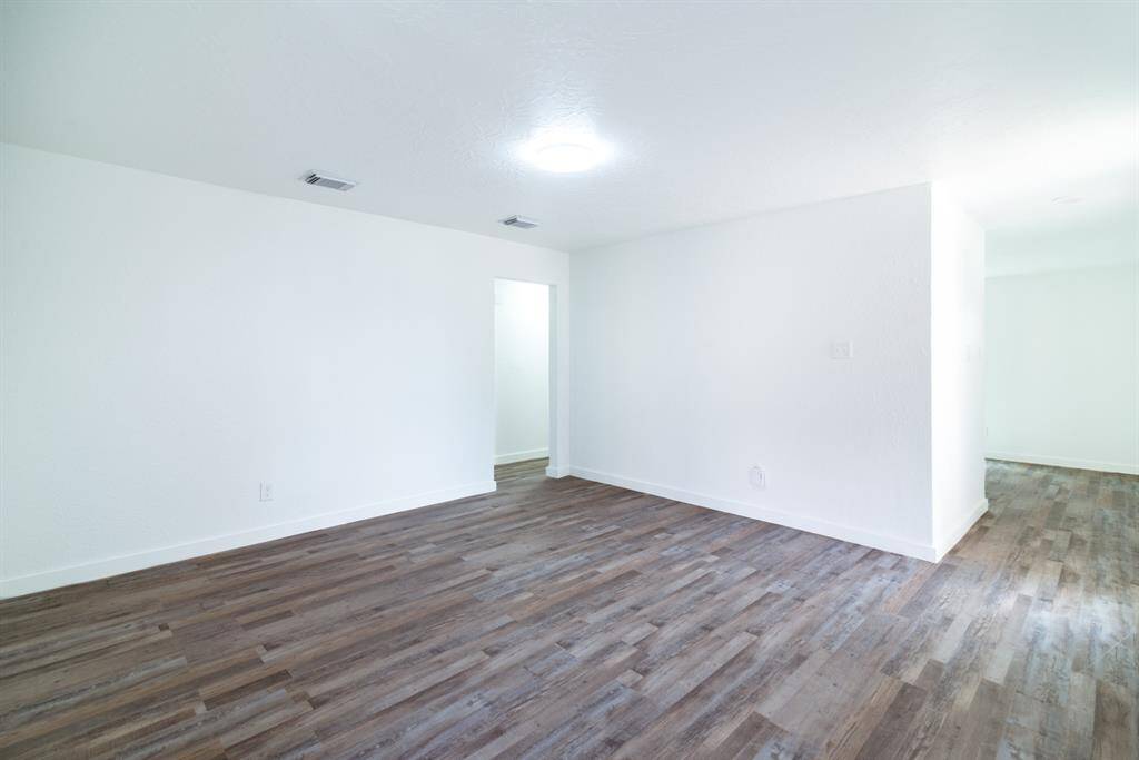 This is a single-story home with a two-car garage, featuring a clean, light-colored facade. It has a spacious driveway and a small front lawn, with a backdrop of trees adding to its curb appeal.