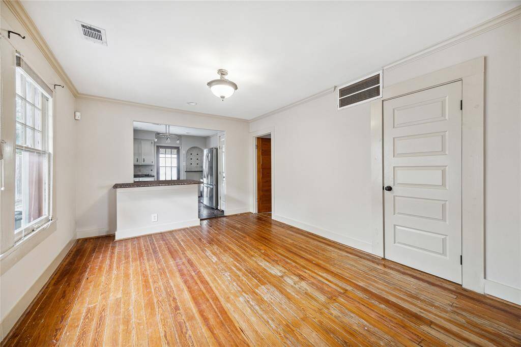 Charming wood floors throughout the property. View of dining room and breakfast bar from living area. Abundance of natural light and half bath centrally located.