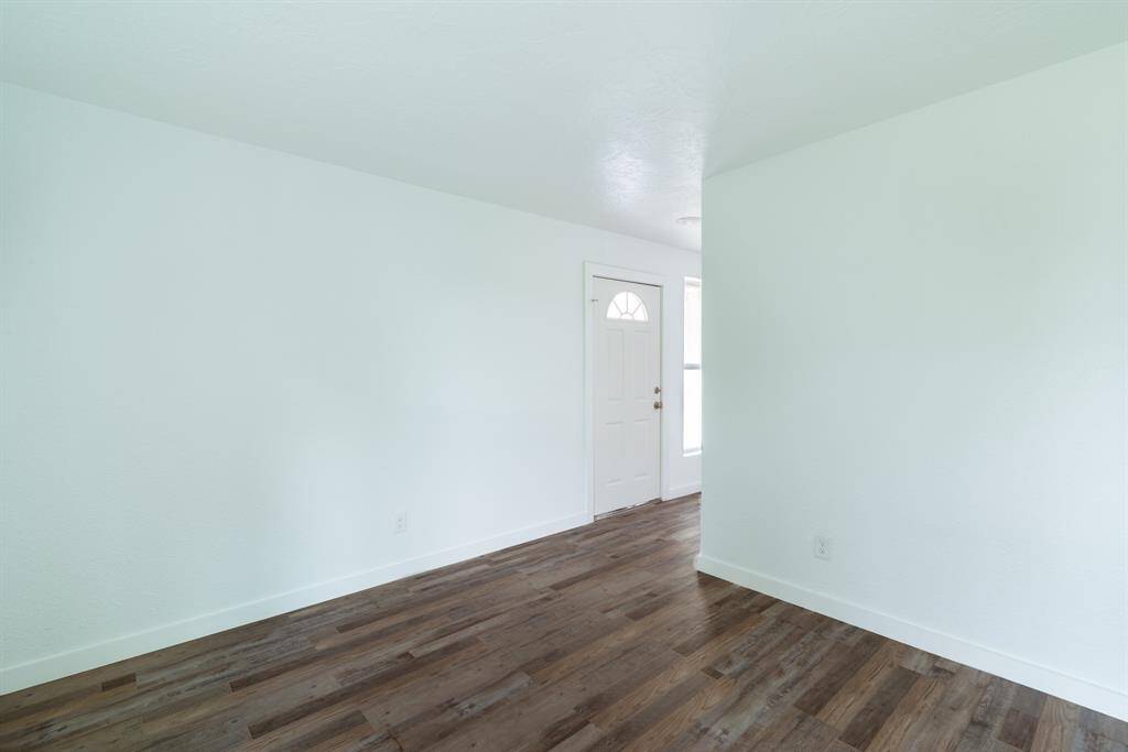 This photo showcases a bright, spacious room with hardwood flooring and white walls. The room features a large window and glass doors leading to the outside, providing plenty of natural light.