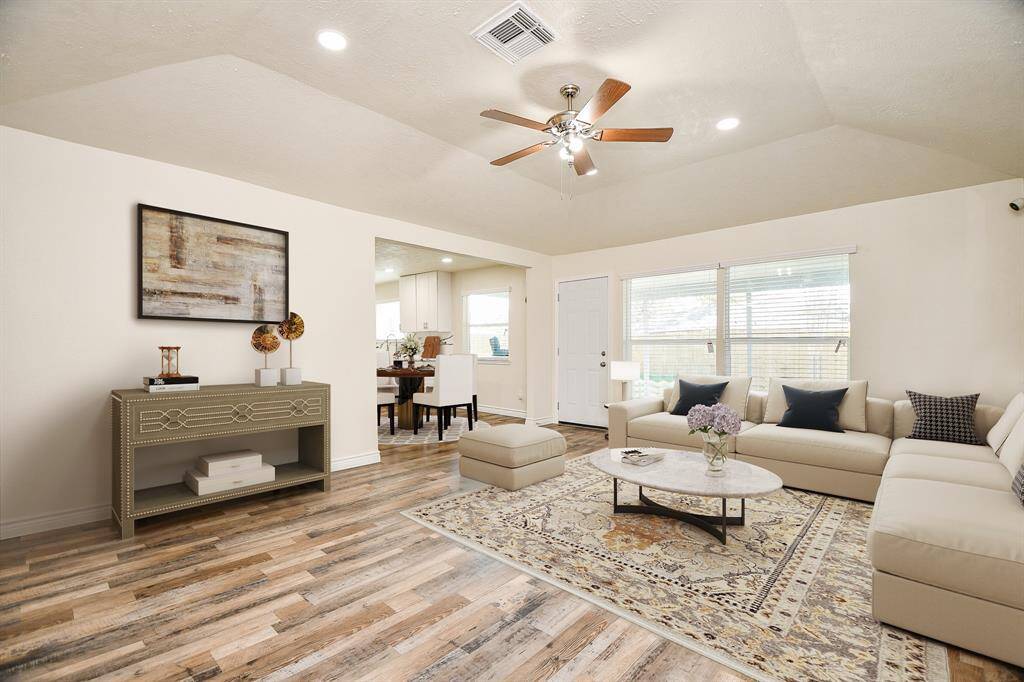 Virtually Staged: This beautiful living room features new recessed lighting and a vaulted ceiling with a ceiling fan, laminate wood floors, and TONS of natural light. It has easy access to the dining room.