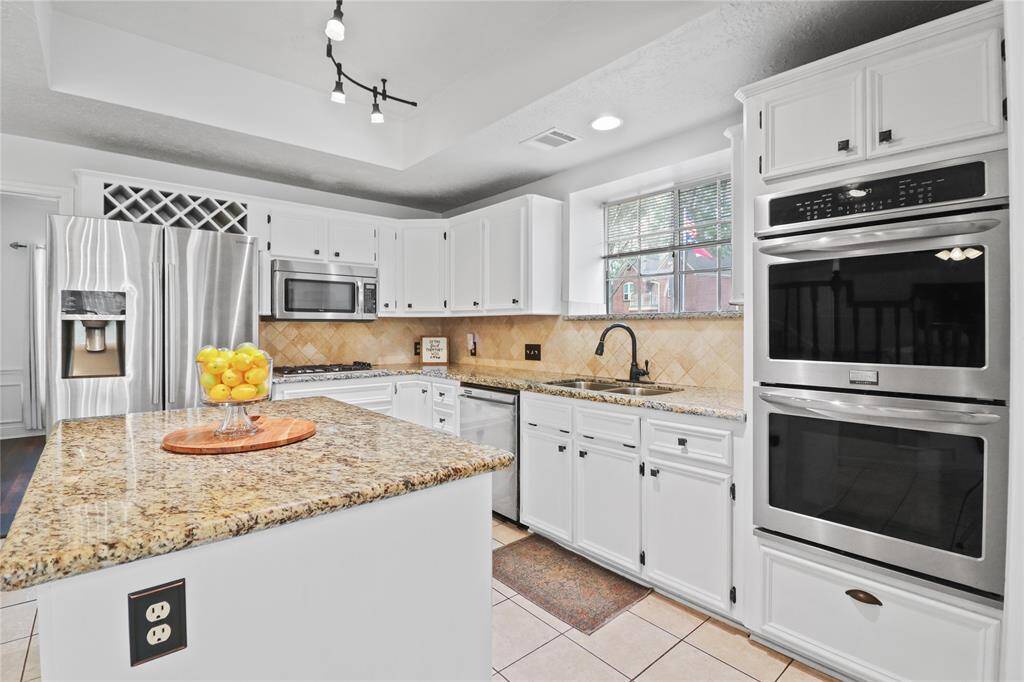 Spacious island kitchen featuring double ovens and a gas range for gourmet cooking.
