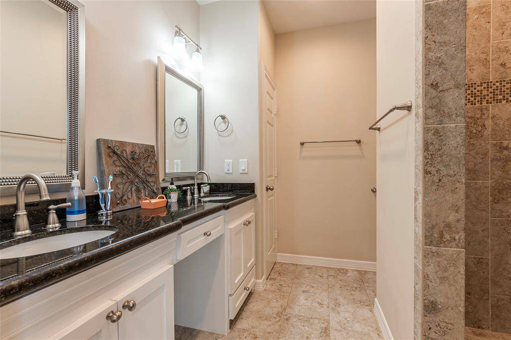 This spacious bathroom features a stylish double vanity with a sleek granite countertop, offering plenty of room for storage and daily routines. The elegant design adds a touch of luxury, while the durable granite surface provides both beauty and functionality. Perfect for shared spaces, this vanity enhances convenience without compromising on style.