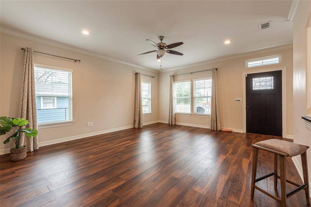 The spacious living room is surrounded by windows, filling the space with natural light. Perfect for entertaining and gathering with family and friends with easy access to the kitchen and dining area.