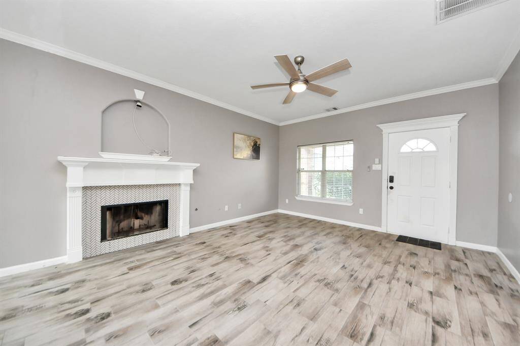 The bright living room has modern flooring, neutral gray walls, and a cozy fireplace.