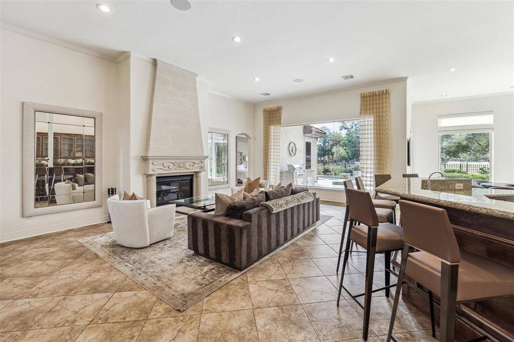 The lovely cast stone fireplace anchors this space with views of the loggia, outdoor kitchen, pool and golf course.