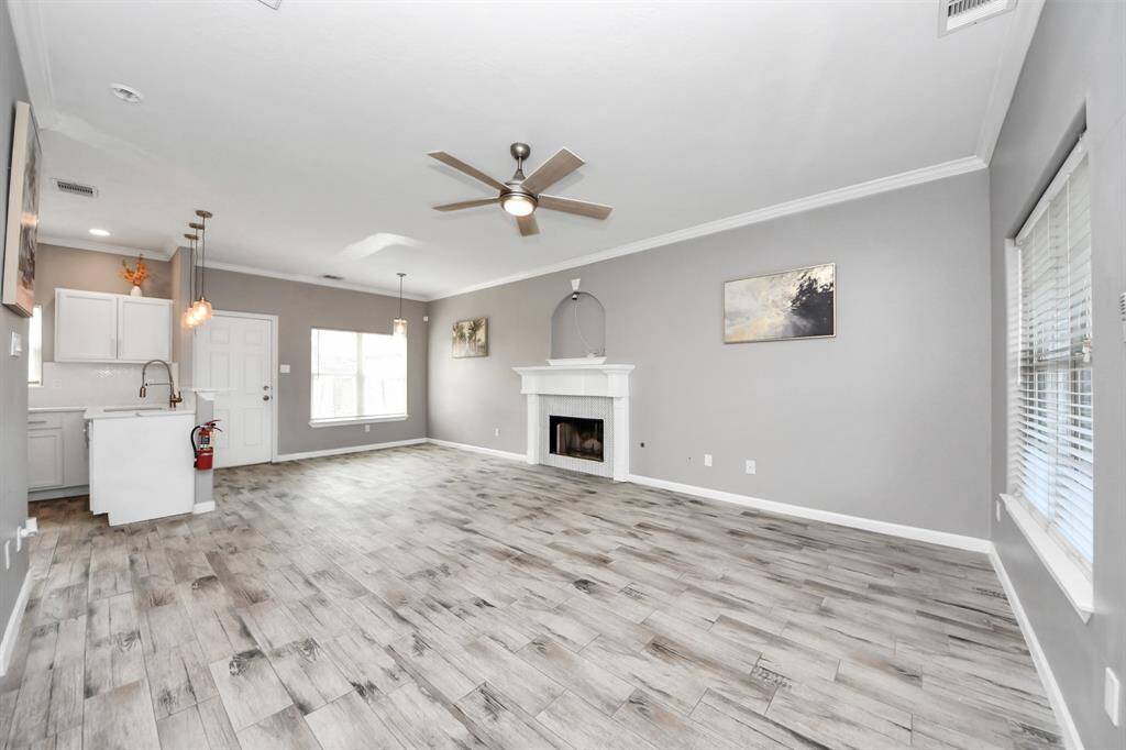 Bright living room with modern flooring, neutral gray walls, and a cozy fireplace.