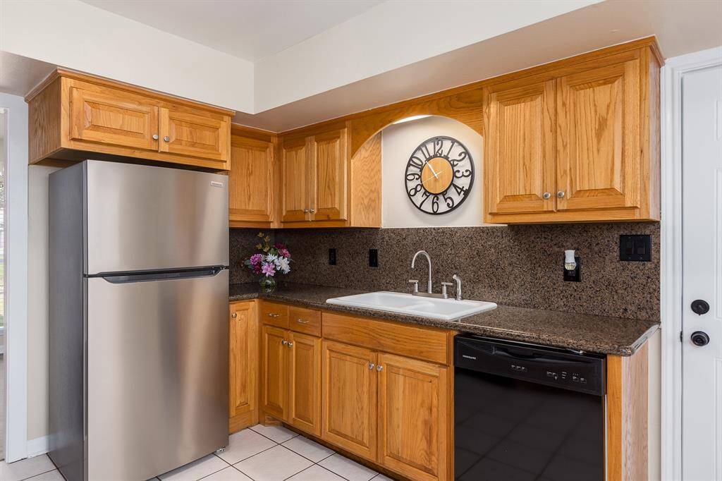 Kitchen features sleek stainless steel appliances, elegant granite countertops, and ample wooden cabinetry for stylish functionality.