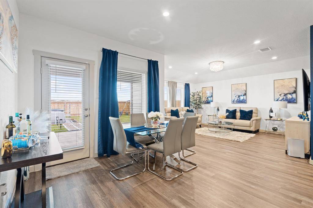 This is a modern, open-concept living and dining area with premium laminate floors, and abundant natural light. Doors leading to an outdoor space, and the room features a contemporary neutral color palette. Approximate Measurements: 11X10