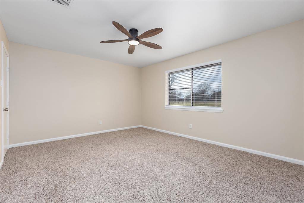 Spacious master bedroom featuring plush carpeting, modern ceiling fan, and ample natural light from large window.