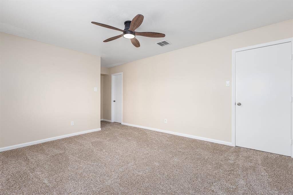 Spacious master bedroom featuring plush carpeting, fresh paint, and a sleek ceiling fan for comfort and style.