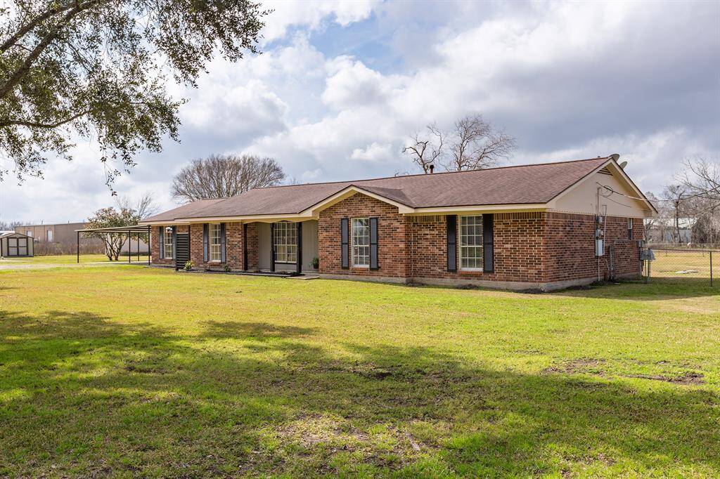 This charming single-story brick home features a spacious front yard with mature trees, offering plenty of outdoor space. The house has a classic design with a gable roof and large windows, providing ample natural light. Ideal for those seeking a comfortable and inviting property in a serene setting.