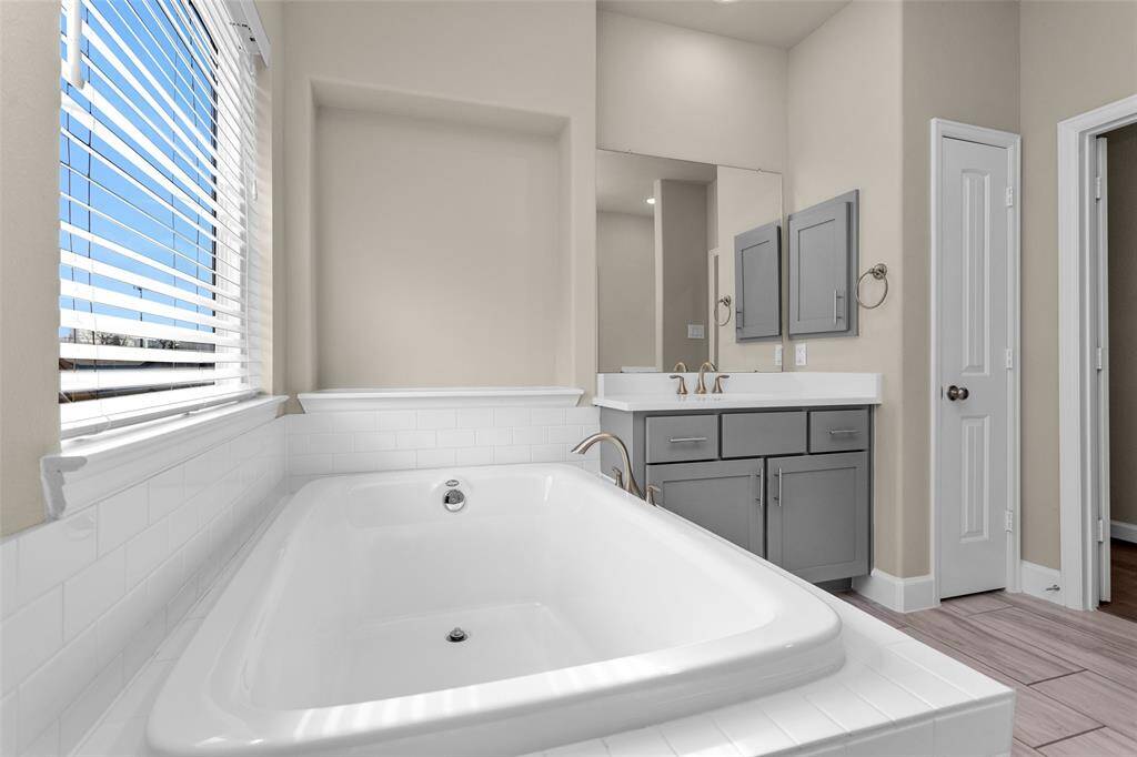 The primary bathroom is like a spa retreat featuring a soaking tub with subway  tile enclosure, double sinks, and an oversized walk in shower.
