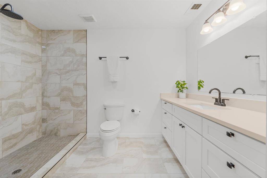 The updated primary bath features an expanded stand-up shower and a stunning vanity with a single sink, offering plenty of storage space to keep everything organized and easily accessible.