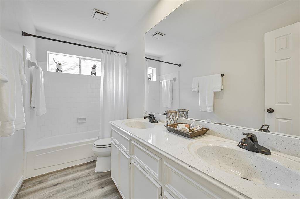 The spacious and well-lit secondary bathroom offers a soaking tub with shower and double sinks.
