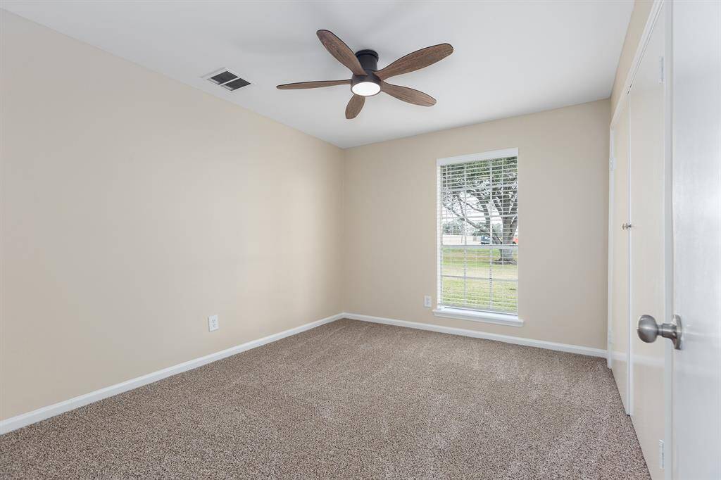 Cozy and bright second bedroom featuring plush carpeting, a modern ceiling fan, and a large window for natural light.