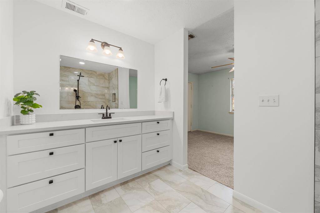 The stunning vanity features a sleek design with ample storage, offering both style and functionality to the updated primary bath.
