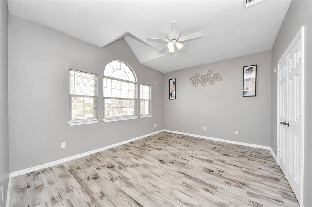 Primary bedroom suite features light wood-look flooring, a ceiling fan and a window to provide natural light.