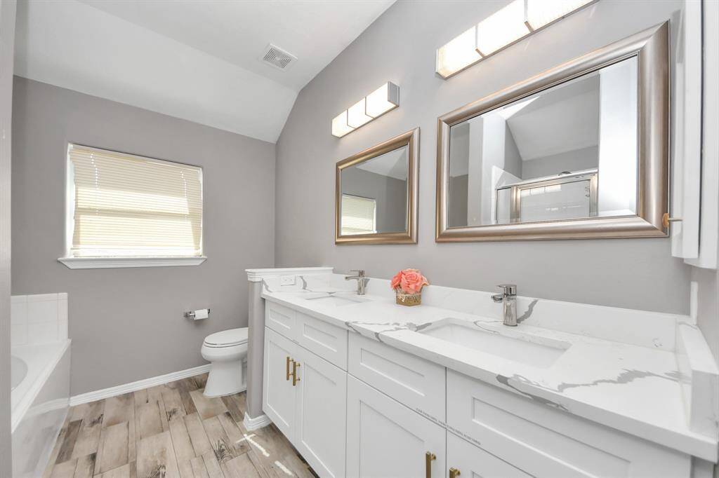The primary bathroom features double sinks, stylish lighting and framed mirrors for the convenience of the owner(s) of the home.