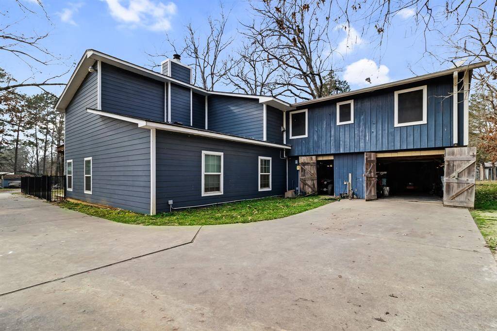 Rear view of the home highlighting the attached garage and spacious backyard, offering easy access to outdoor features like the pool, patio, and additional parking.