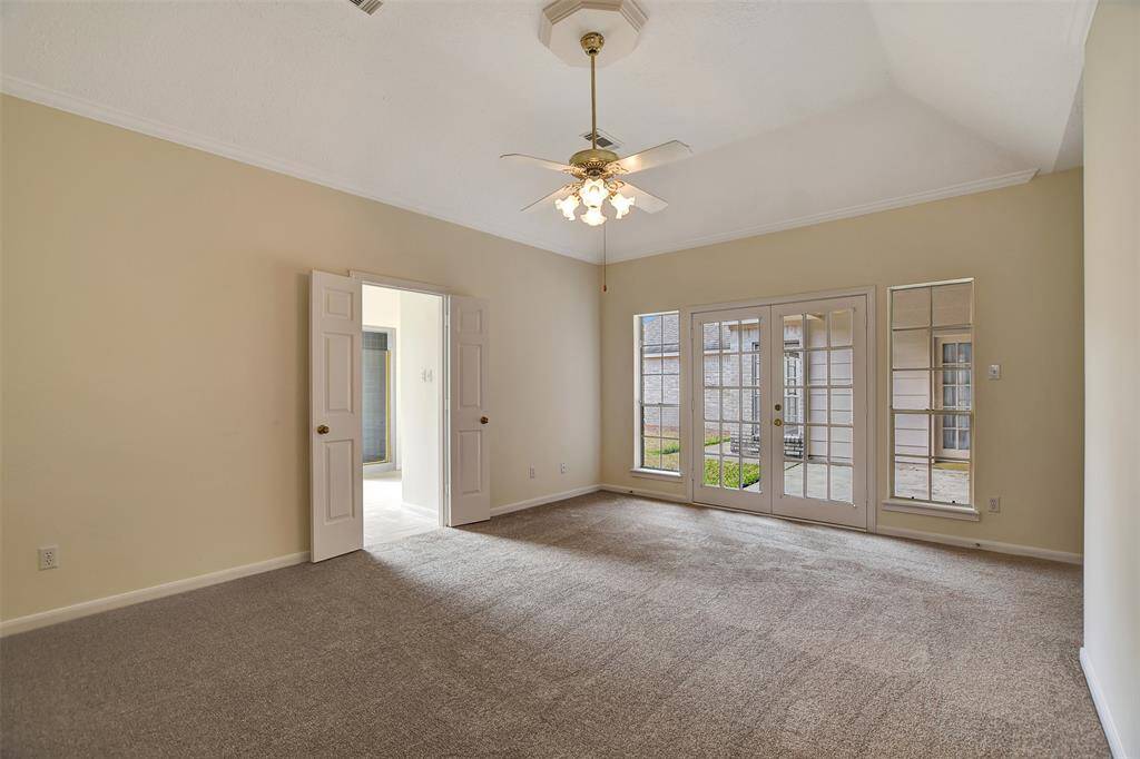 Primary bedroom with doors leading out to covered patio.