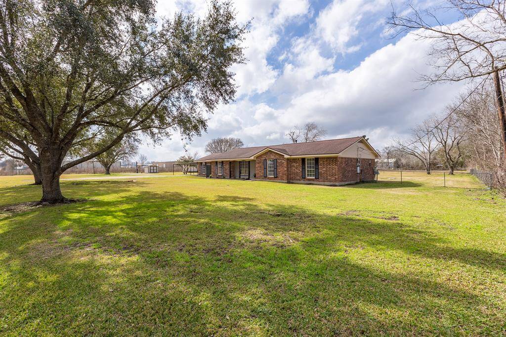 This photo showcases a spacious single-story brick home set on a large grassy lot with mature trees, offering ample outdoor space and a serene environment.