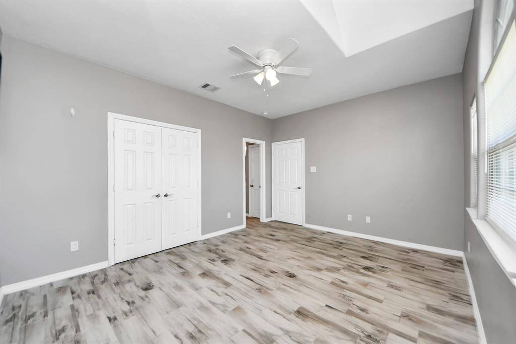 This bright room features light flooring, neutral gray walls, a ceiling fan and offers a modern and airy feel.