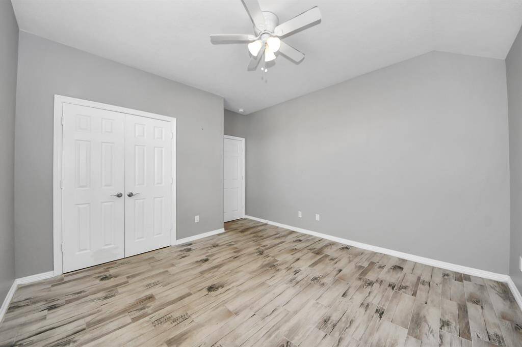 This bright room features light flooring, neutral gray walls, a ceiling fan and offers a modern and airy feel.