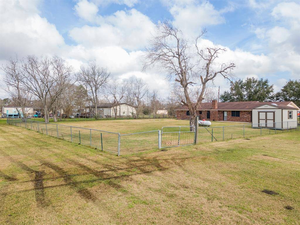 Spacious fenced yard with mature trees, a shed, and a single-story brick house in a quiet neighborhood. Ideal for families seeking outdoor space.