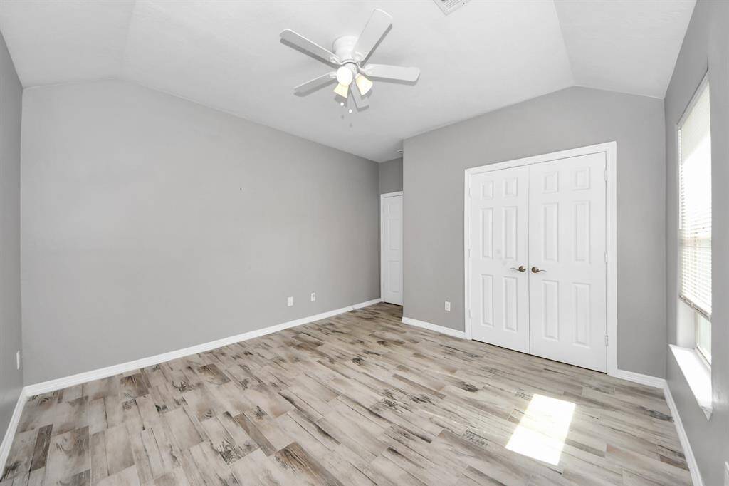 This bright room features light flooring, neutral gray walls, a ceiling fan and offers a modern and airy feel.