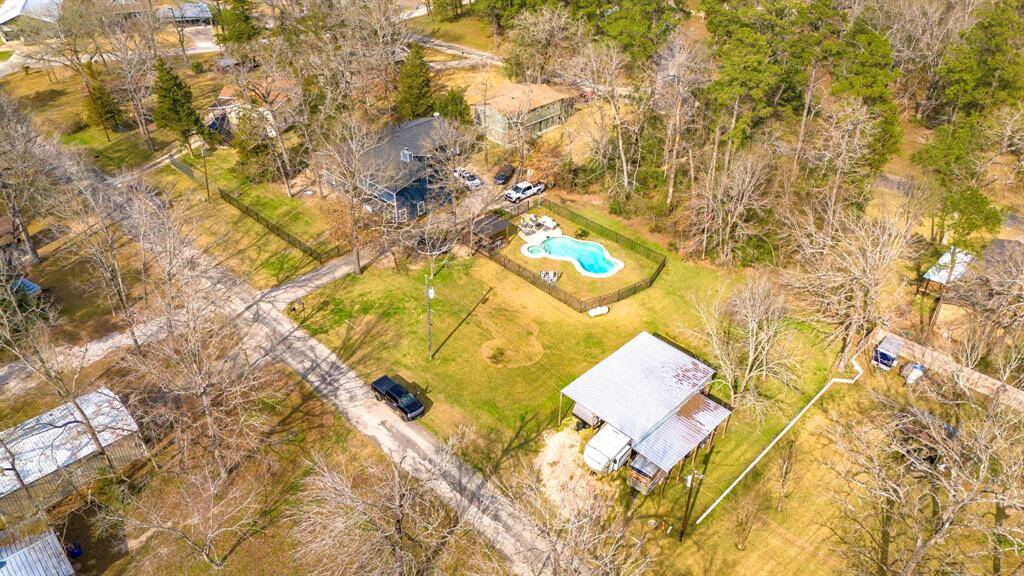 Stunning overhead shot showcasing the home’s front elevation, spacious lot, and serene wooded surroundings near Lake Livingston.