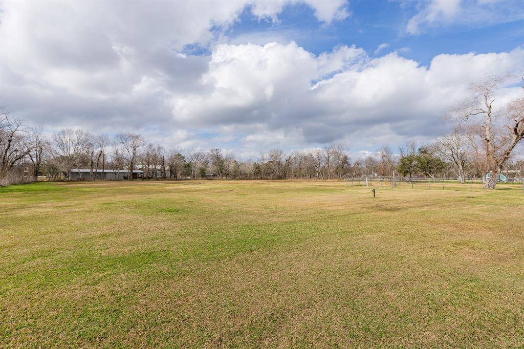Expansive open field with lush grass, surrounded by trees. Ideal for building or outdoor activities, offering a tranquil rural setting under a partly cloudy sky.