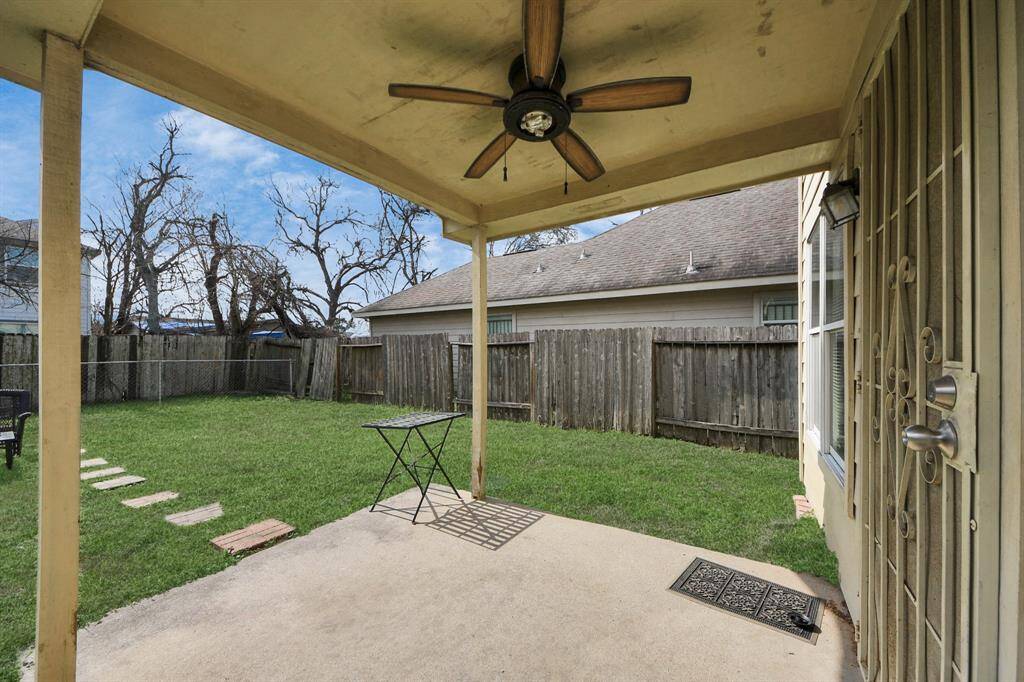 Cozy backyard with a covered patio. The yard is fenced, with a grassy area and stepping stones, offering a private outdoor space.