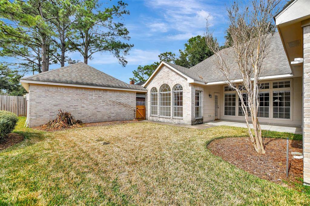 This photo shows a charming backyard with a well-maintained lawn. The setting is serene offering privacy and a pleasant outdoor space.