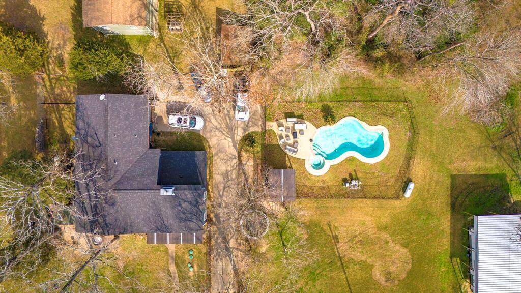 Stunning overhead shot showcasing the home’s front elevation, spacious lot, and serene wooded surroundings near Lake Livingston.