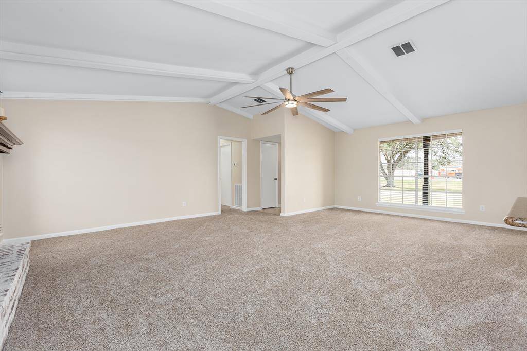 Spacious living room with vaulted ceilings, large window for natural light, and cozy carpeting—perfect for relaxation and gatherings.