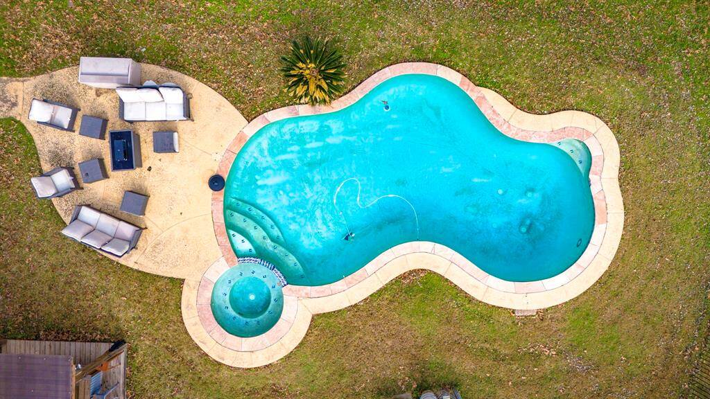 Birds-eye perspective of the private backyard oasis featuring a pool, hot tub, and outdoor entertaining space.