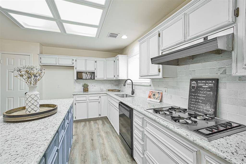 White granite, white backsplash, huge ceiling light panels, and a sink window make this kitchen the brightest spot in the house.