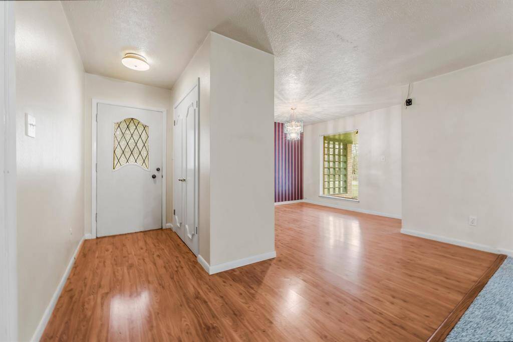 Step inside and admire the welcoming hallway and formal dining area, both featuring light wood laminate flooring that creates a warm and inviting atmosphere.