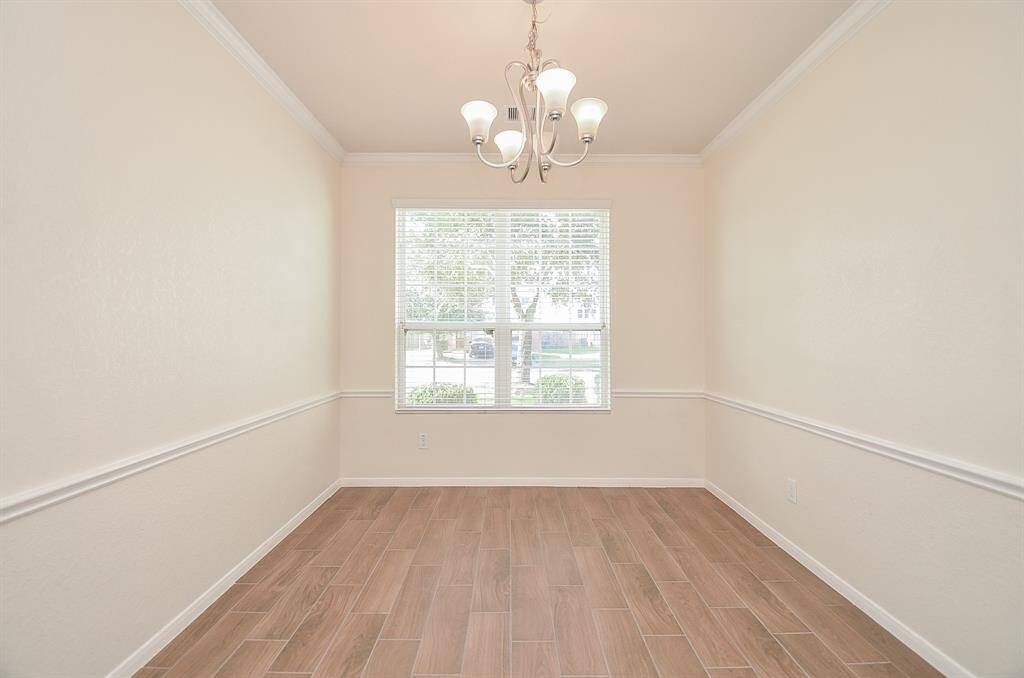 Warm memories will fill the formal dining area, just off the kitchen; featuring creamy beige walls with classic crown molding; newly installed wood-look tile, and a large double window to bathe this space in glorious natural rays.