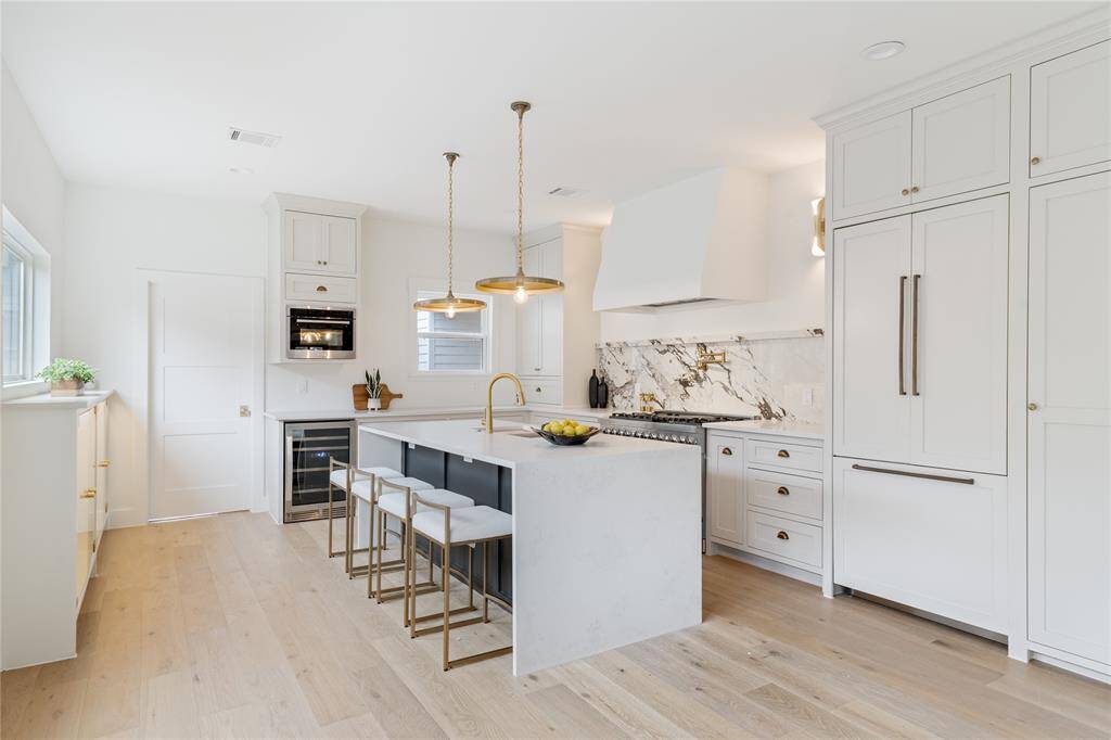 A chef’s dream kitchen with custom cabinetry, high-end appliances, quartz countertops, and a stunning marble backsplash.