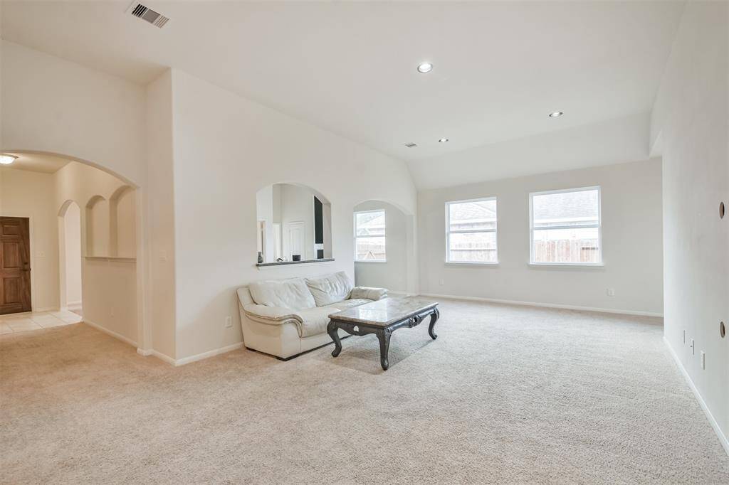Open-concept family room featuring elegant arched entryways and detailed picture frame molding.