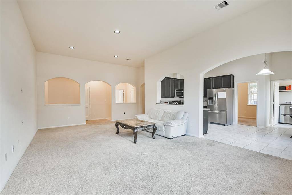 A cozy family room seamlessly flows into the kitchen through an elegant arched entryway.