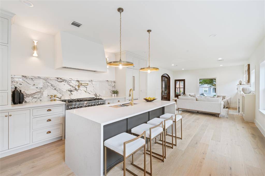 Prepare to be amazed by the open kitchen concept with custom white oak cabinetry from floor to ceiling, under cabinet lighting and stunning quartz countertops and slab backsplash.
