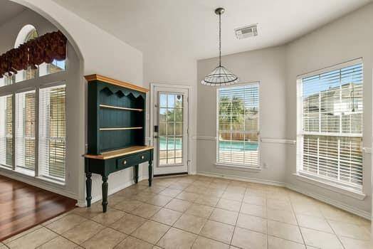 Bright room with large windows and tile flooring, offering a view of a pool. It features  a door leading outside. Perfect for a sunlit dining area or breakfast nook.