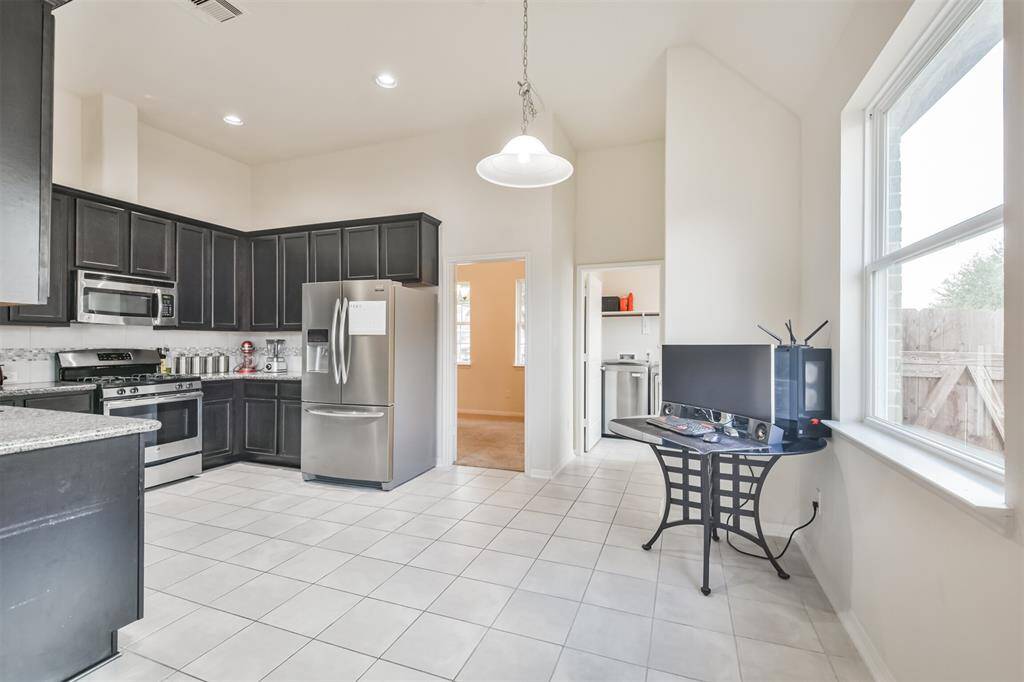 A kitchen featuring sleek canister lighting and elegant ceramic tile flooring, complete with a charming breakfast nook.